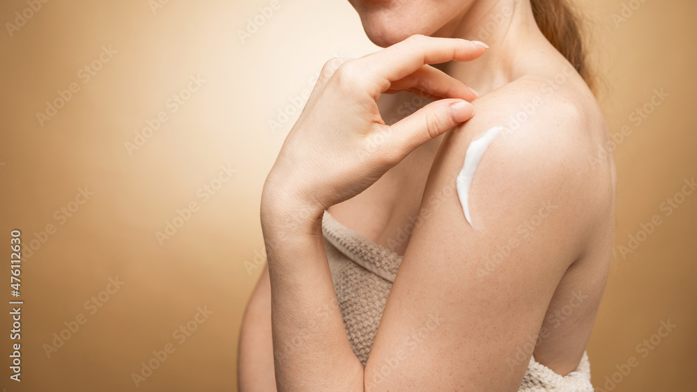Fototapeta premium A woman after a spa uses a skin cream for hydration and youth.