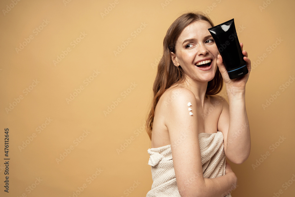 Fototapeta premium The woman uses a new body skin cream, moisturizing and scrub. The model shows cosmetics after the spa.