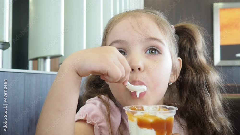 Happy surprised little girl serving ice cream .The child sits at a table in a cafe and is happy A happy childhood. cute beautiful girl eating ice cream in a cafe. sweets. family vacation. positive emo Happy surprised little girl serving ice cream .The child sits at a table in a cafe and is happy A happy childhood. cute beautiful girl eating ice cream in a cafe. sweets. family vacation. positive emo