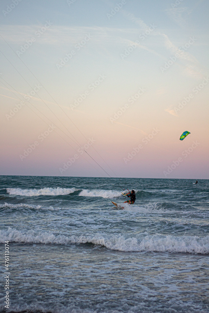 Windsurfing at sunset on a cullera beach. calm sea and vivid colors in the sky