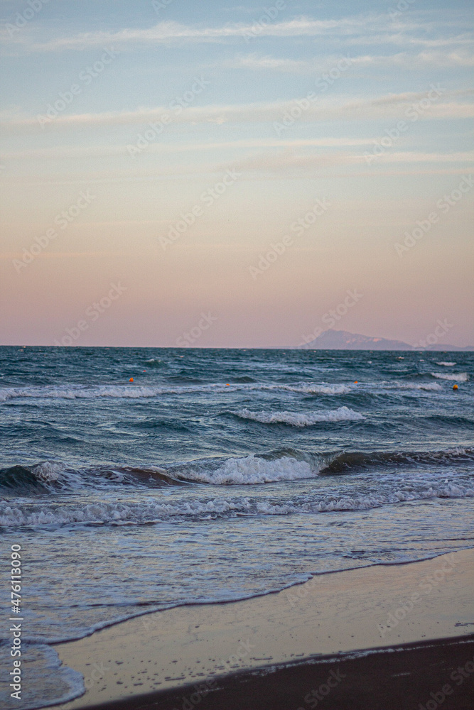 Windsurfing at sunset on a cullera beach. calm sea and vivid colors in the sky