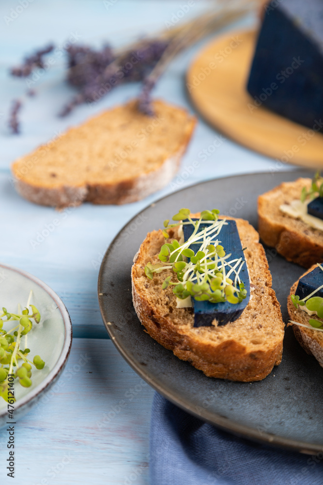 Bread sandwiches with blue lavender cheese and mustard microgreen on blue, side view, selective focus. Bread sandwiches with blue lavender cheese and mustard microgreen on blue, side view, selective focus.