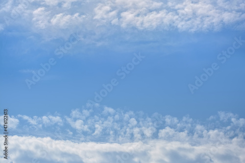 Two horizontal stripes of clouds  between which there is a clear blue space of the sky