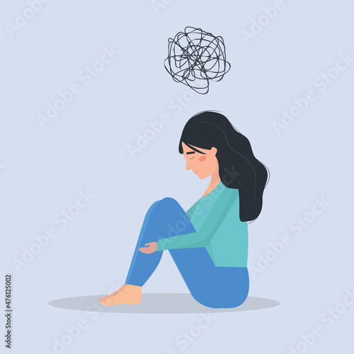 Mental health issues. Depressed woman sitting on the floor and holding her knees.