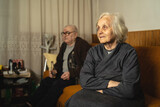 Senior caucasian woman and man pensioner husband and wife sitting on the couch at home - Old age people married couple retirement and togetherness concept selective focus on female