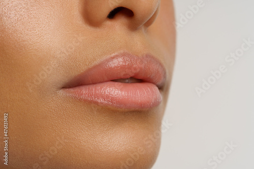 Obraz na plátne Close up photo of moisturized smooth lips of african american woman using chapstick or moisturizing lip balm to nourish, hydrate and protect from cold