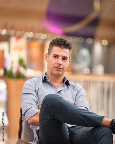 A young joyful business man posing for a portrait photograph inside an empty city mall in the heart of Lisbon, Portugal. Young attractive freelance architect wearing a classy shirt and formal outfit