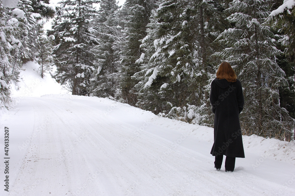 Female walking on cold snowy road.