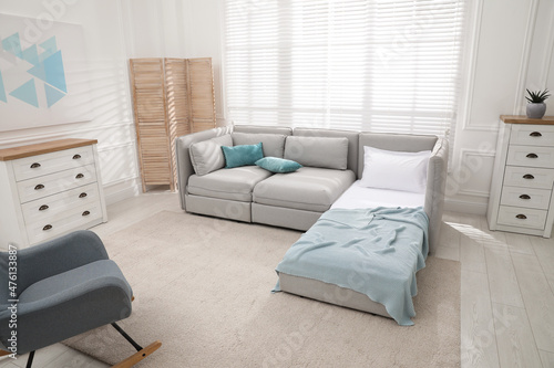 Stylish room interior with sleeper sofa and rocking chair. Additional place for guest