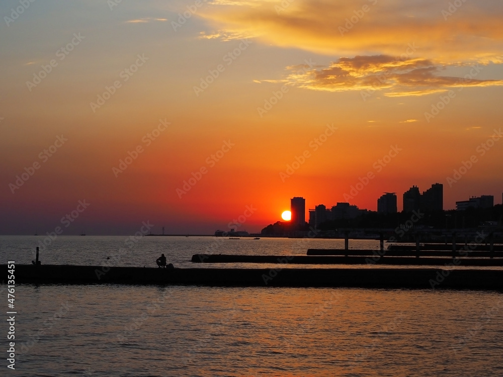The sun sets in the sunset bright sky above the high houses on the seashore. Sea sunset The sun sets in the sunset bright sky above the high houses on the seashore. Sea sunset