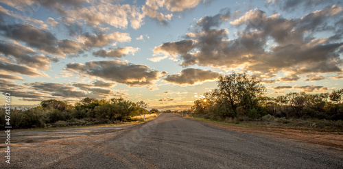 Fotografie, Obraz Asphalt road through the dry nature under the sunset sky