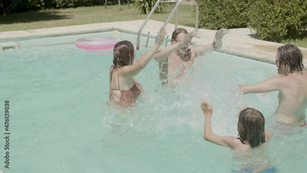 Excited parents and kids splashing water on each other in pool. Happy Caucasian dad, mom and sons having fun, laughing, enjoying life and spending time together at summer party. Family, joy concept Excited parents and kids splashing water on each other in pool. Happy Caucasian dad, mom and sons having fun, laughing, enjoying life and spending time together at summer party. Family, joy concept