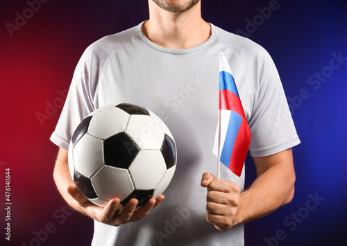 Football fan with ball and flag of Russia on dark background © Pixel-Shot
