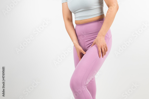 In a white background, a woman is touching her sore legs and knees.
