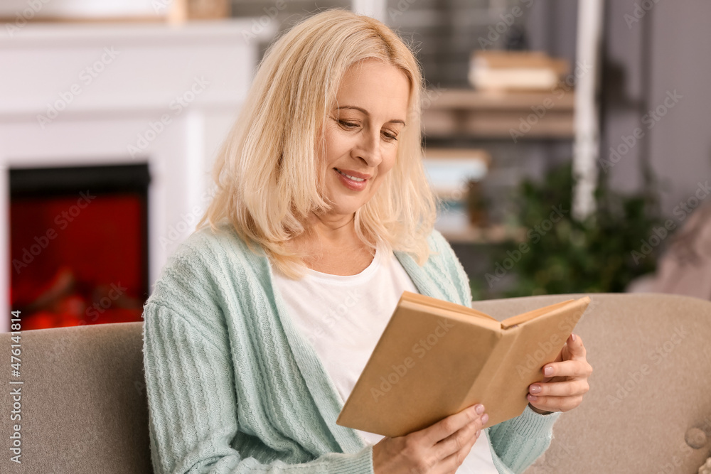 Beautiful mature woman reading book at home on autumn day Beautiful mature woman reading book at home on autumn day