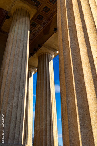 Three supporting columns in an ancient greek architectural style building during bright sunny day