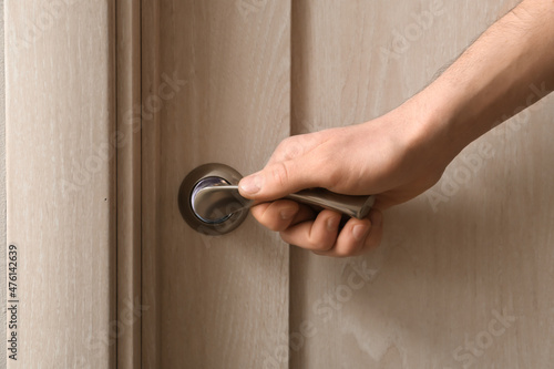 Man opening light wooden door at home, closeup