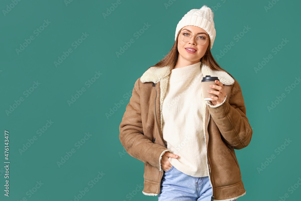 Beautiful young woman in winter clothes and with cup of coffee on color background Beautiful young woman in winter clothes and with cup of coffee on color background
