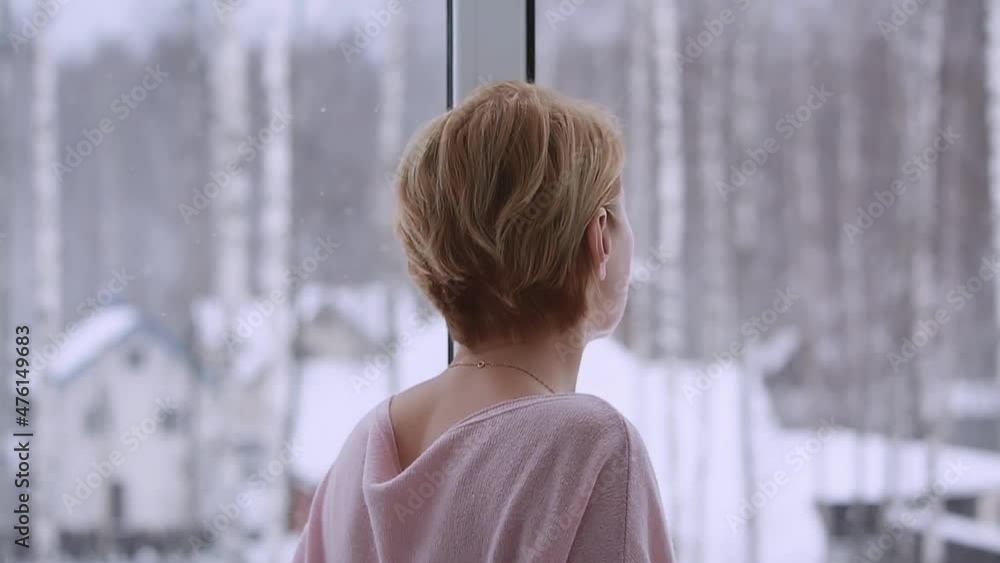 A woman looking out the window in winter A woman looking out the window in winter