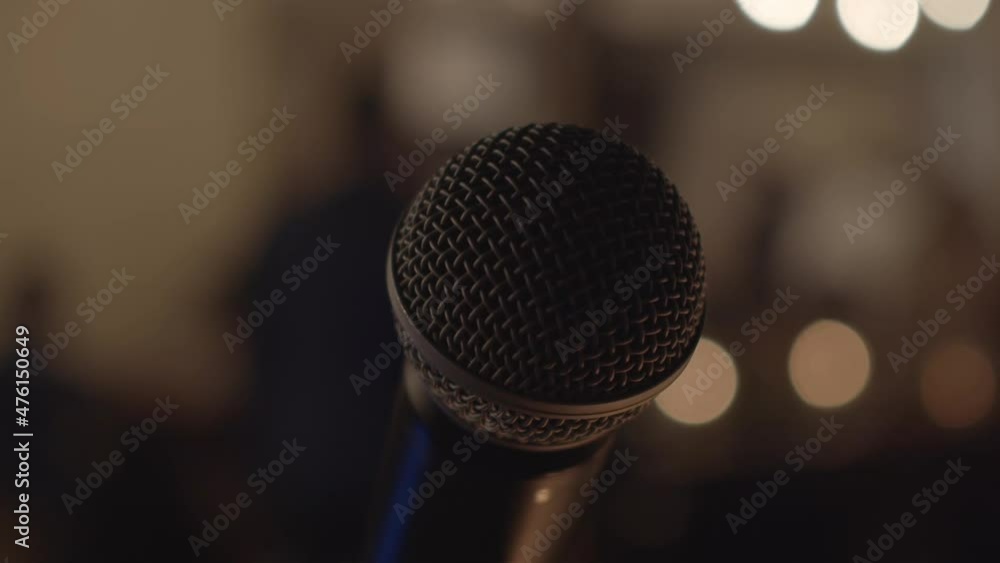 Circular view of a professional microphone on an evening stage in a building with blurred background and lights Circular view of a professional microphone on an evening stage in a building with blurred background and lights