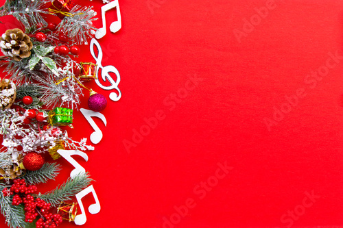 Composition with notes and christmas decorations on red background.