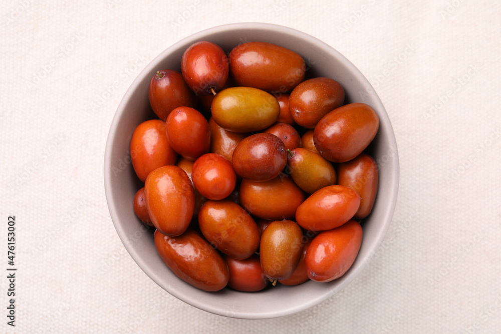 Fresh Ziziphus jujuba fruits in bowl on white tablecloth, top view Fresh Ziziphus jujuba fruits in bowl on white tablecloth, top view