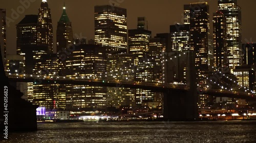 View of New York City skyline illuminated at night with Brooklyn bridge over the river, panoramic cityscape at dusk