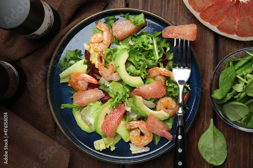 Delicious pomelo salad with shrimps served on wooden table, flat lay