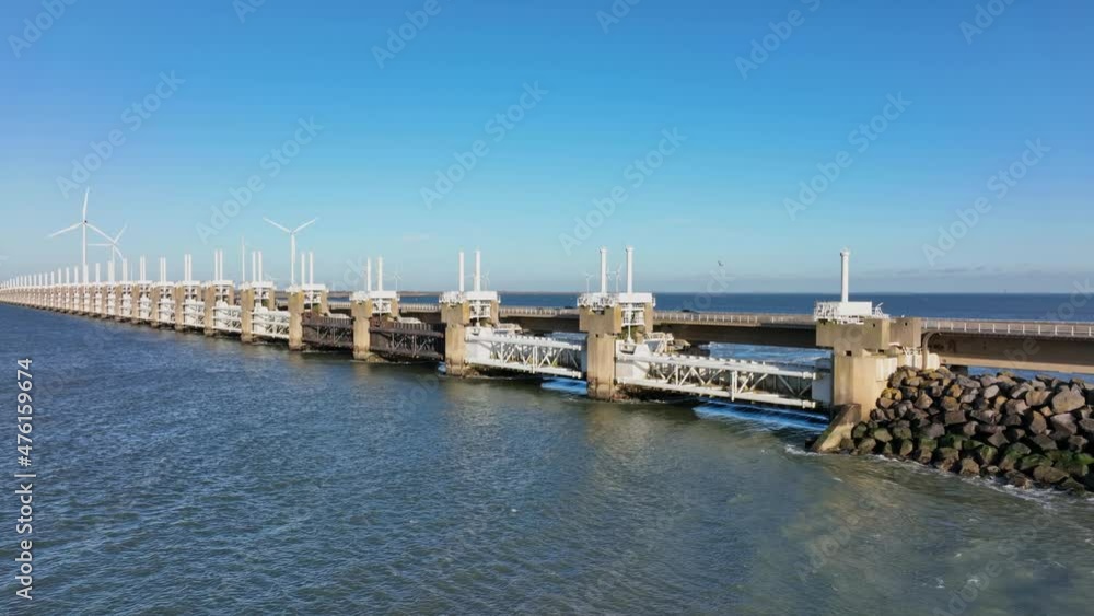 Aerial slow motion shot of the Eastern Scheldt storm surge barrier and wind turbines in Zeeland, the Netherlands on a beautiful sunny day with a blue sky Aerial slow motion shot of the Eastern Scheldt storm surge barrier and wind turbines in Zeeland, the Netherlands on a beautiful sunny day with a blue sky