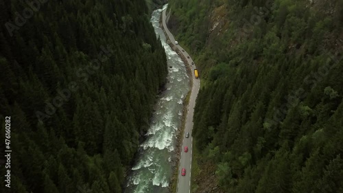 a road surrounded by mountains, pine trees and a river. The road is heading to Odda, Norway. photo