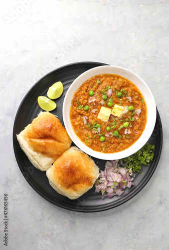  Indian Mumbai Street style Pav Bhaji, garnished with peas, raw onions, coriander, and Butter. Spicy thick curry made of out mixed vegetables served with pav over white background with copy space.