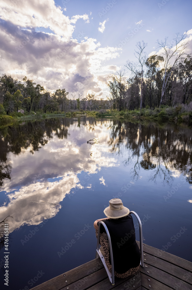Obraz premium woman contemplating quietly by platypus pool. sky reflections.Boonoo Boonoo National Park