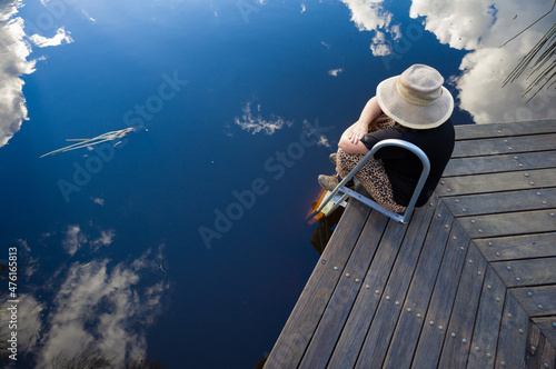 woman contemplating quietly by platypus pool. sky reflections.Boonoo Boonoo National Park