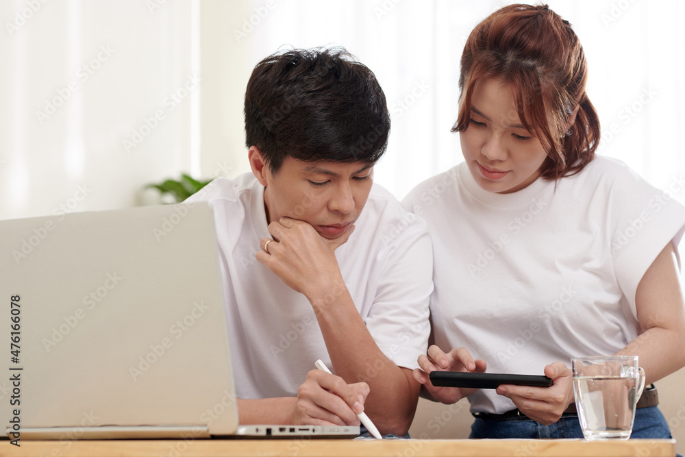 Couple reading fqa on tablet computer when filling health insurance claim form or mortgage documents at home Couple reading fqa on tablet computer when filling health insurance claim form or mortgage documents at home