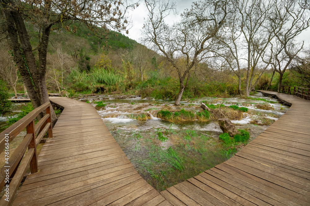 Wooden path at Skradinski buk at Krka waterfalls national park in Croatia. View of a lake path and some foliage around. Wooden path at Skradinski buk at Krka waterfalls national park in Croatia. View of a lake path and some foliage around.