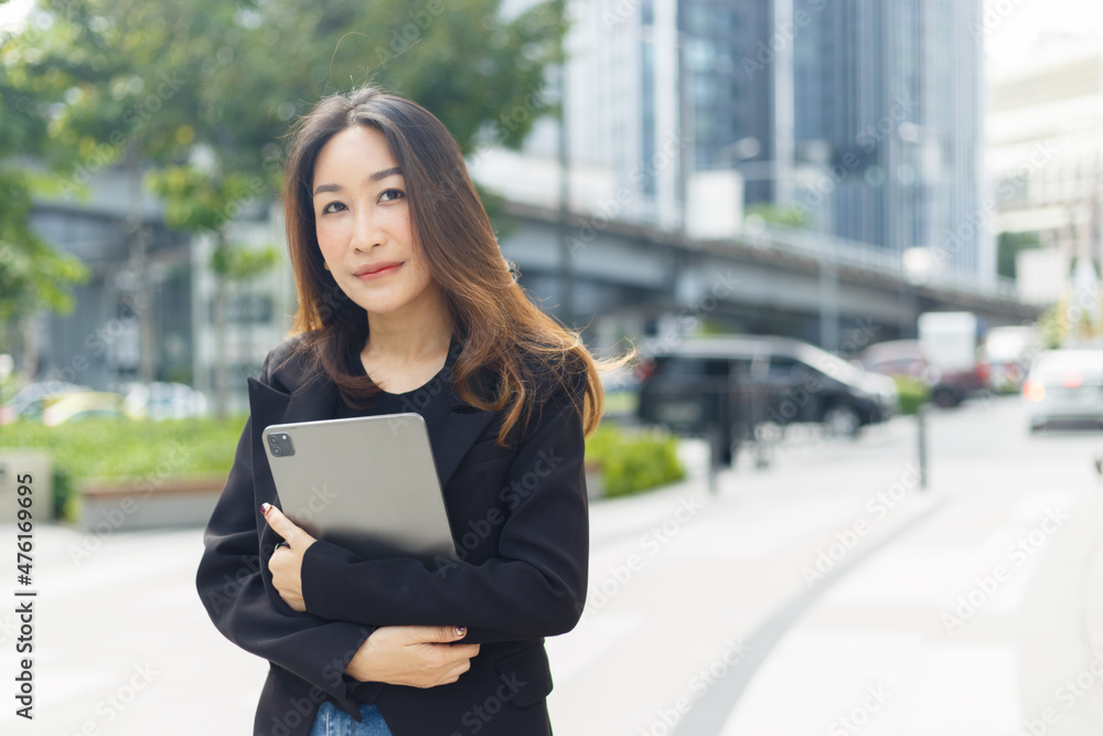 successful asian businesswoman wear black suit holding tablet walking city street. woman freelancer lifestyle human urban. copy space use for text word. successful asian businesswoman wear black suit holding tablet walking city street. woman freelancer lifestyle human urban. copy space use for text word.