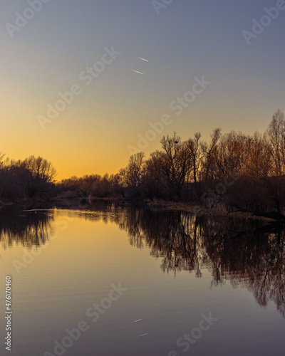 Sunset at coast of the river. Nature landscape with reflection, blue sky and yellow sunlight during sunset