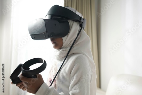 a moslem little girl with hijab playing a game wearing VR glasses