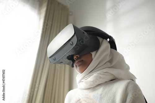 a moslem little girl with hijab playing a game wearing VR glasses