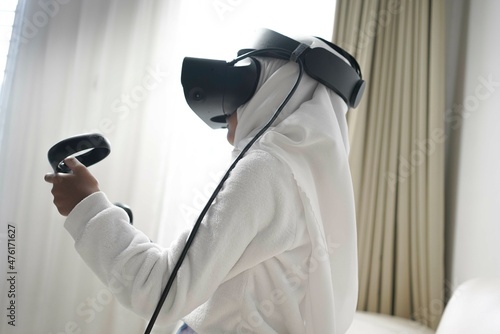 a moslem little girl with hijab playing a game wearing VR glasses