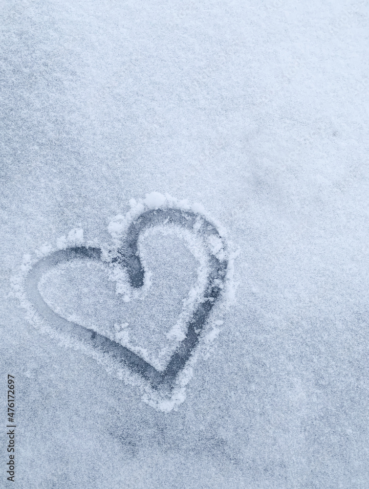 drawn heart on white snow in winter. Vertical photo with a heart drawn in the snow