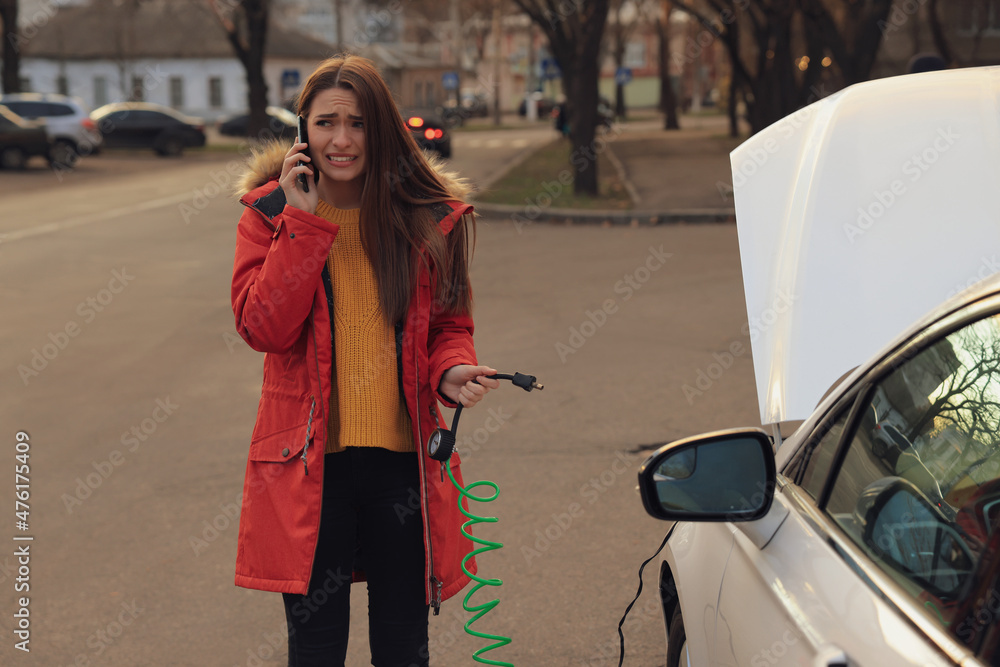 Fototapeta premium Young woman having difficulties while inflating car tire on street