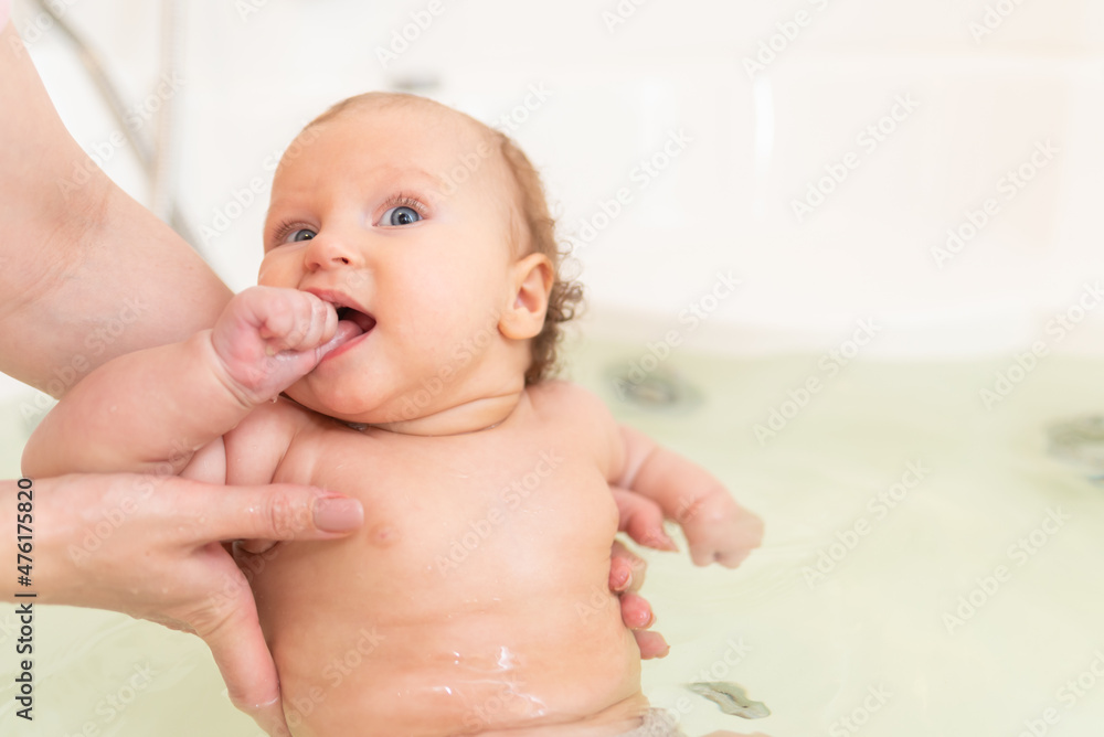 Mom holds the baby in her arms while bathing in the bathroom Mom holds the baby in her arms while bathing in the bathroom