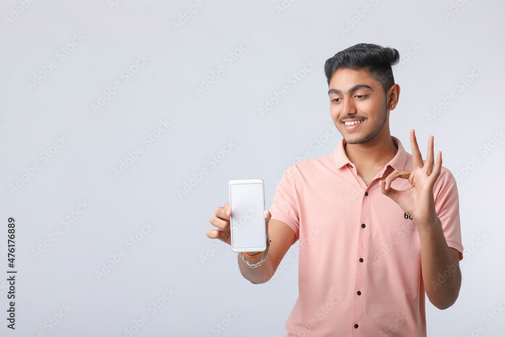 Young indian man showing smartphone screen on white background. Young indian man showing smartphone screen on white background.