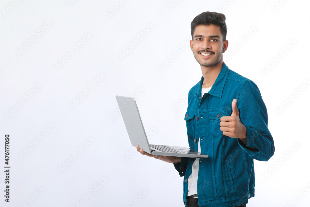 Young indian man using laptop and showing thumps up on white background. Young indian man using laptop and showing thumps up on white background.