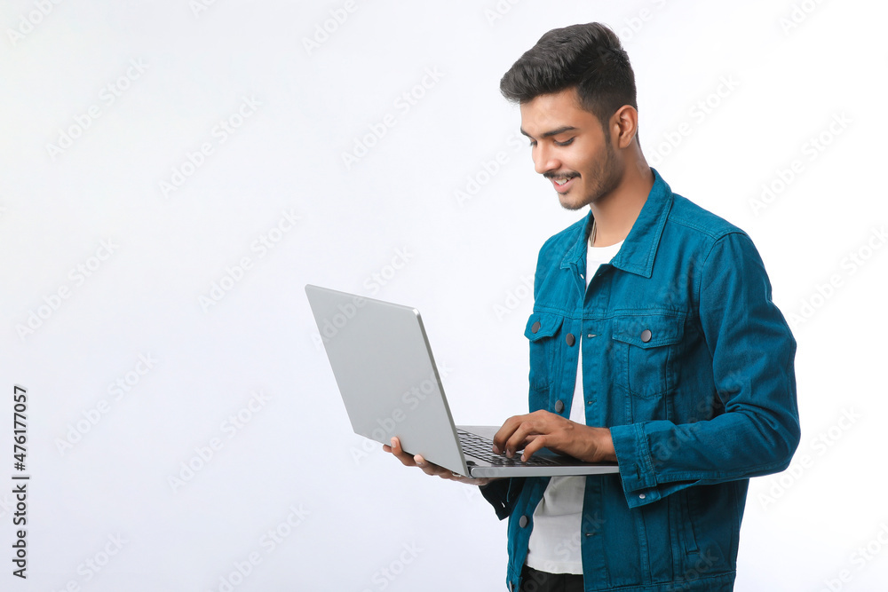 Young indian man using laptop on white background. Young indian man using laptop on white background.