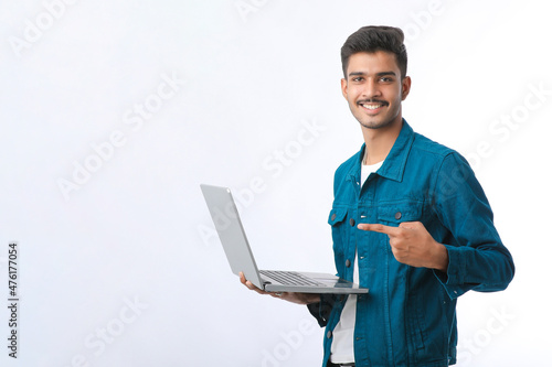 Young indian man using laptop on white background. © Niks Ads