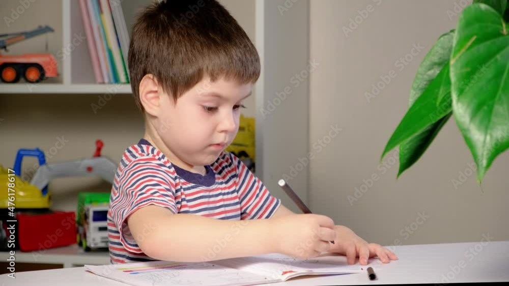 A child of 4 years old learns to write copybook, sits correctly at the table, keeps his back straight. A child of 4 years old learns to write copybook, sits correctly at the table, keeps his back straight.