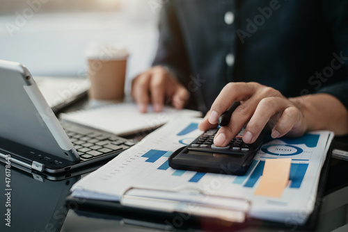 Male businessman working on desk office with using a calculator to calculate the numbers, finance accounting concept.