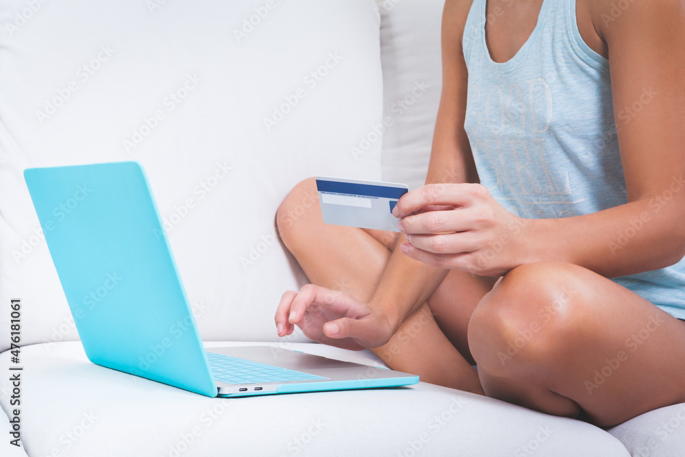Naklejka premium close up young girl using a credit card to shop online at home